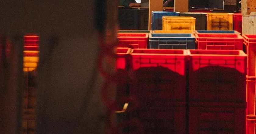 Intralogistics — stacked warehouse crates under a red indicator light, photo by Klara Kulikova on Unsplash