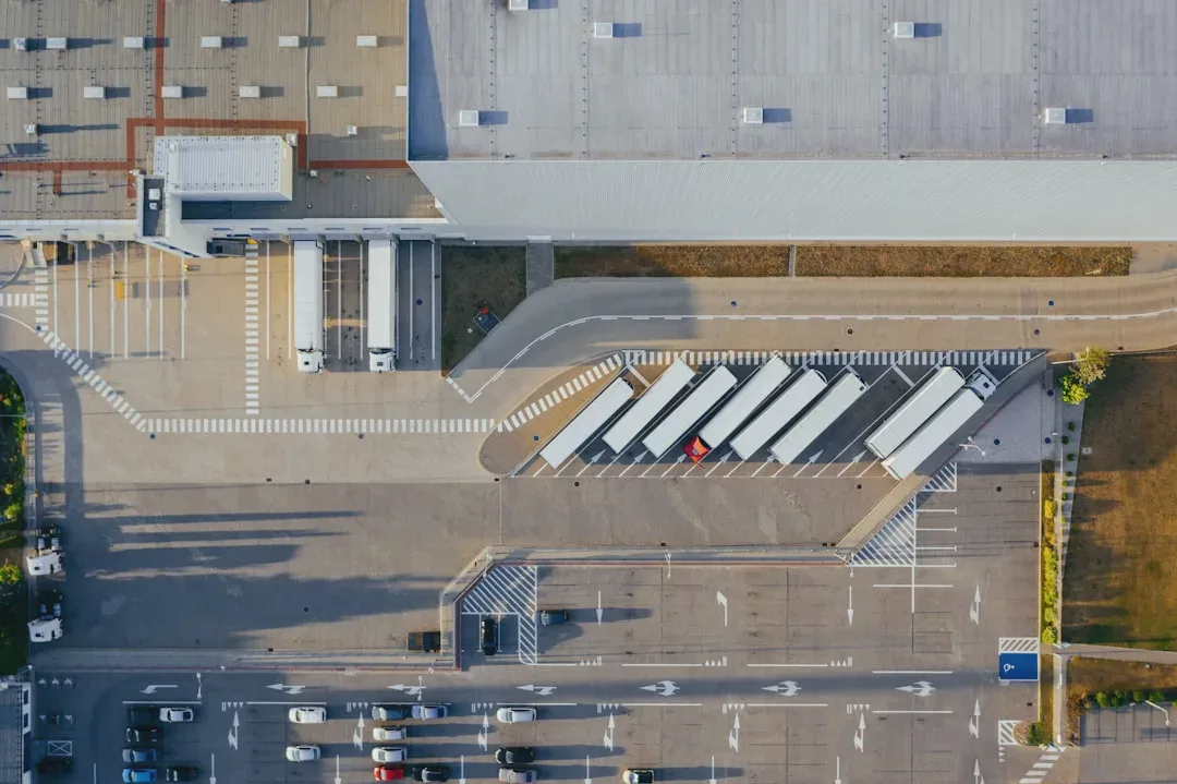 The photo shows an aerial view of a large industrial complex, with numerous trucks parked in designated loading zones and buildings with flat roofs. The surroundings are marked by clear ground signage and orderly parking areas. - Photo: Marcin Jozwiak
